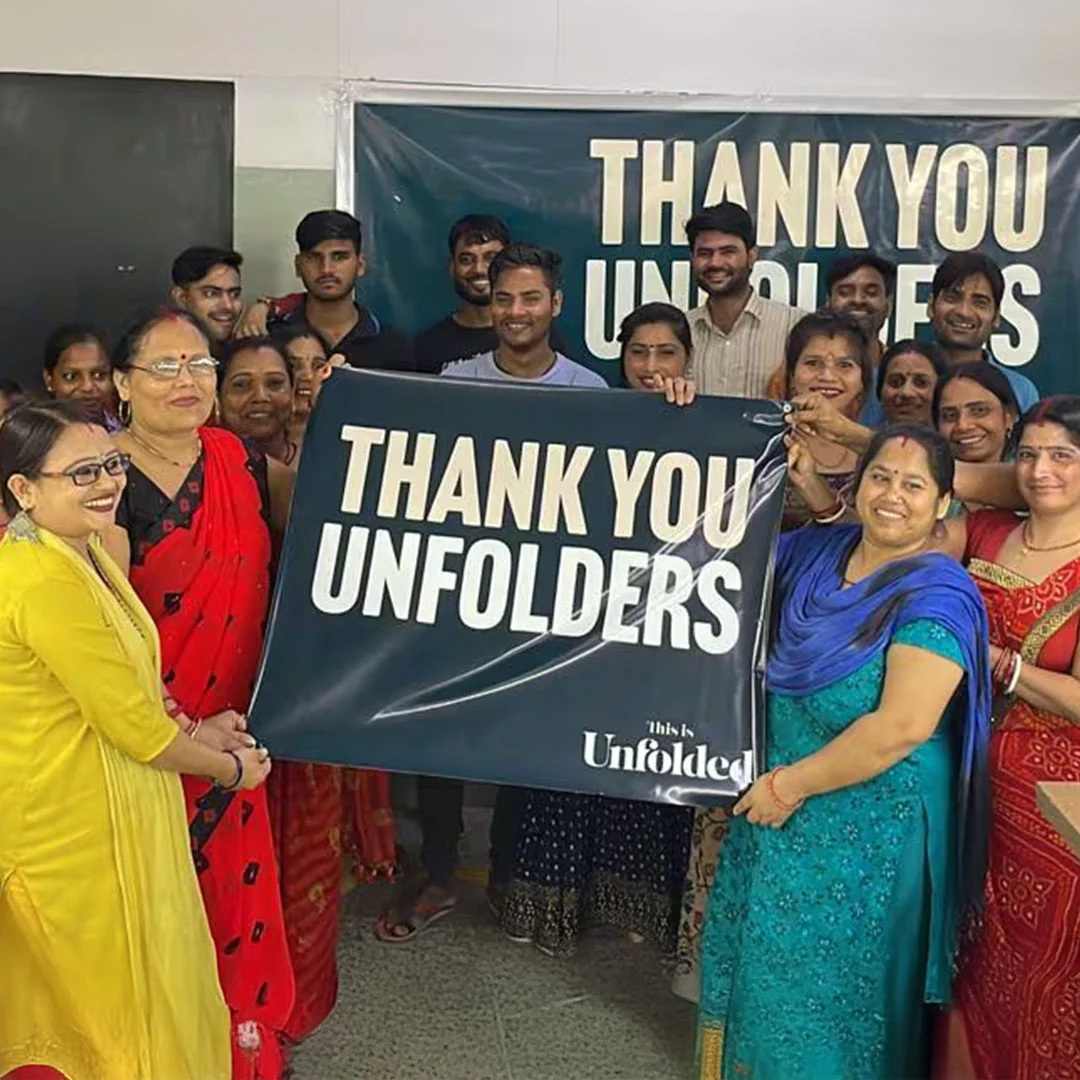 Group of people holding a 'Thank You Unfolders' banner, smiling.