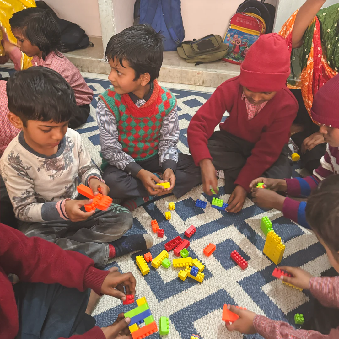 Children sitting on a rug playing with colorful building blocks.
