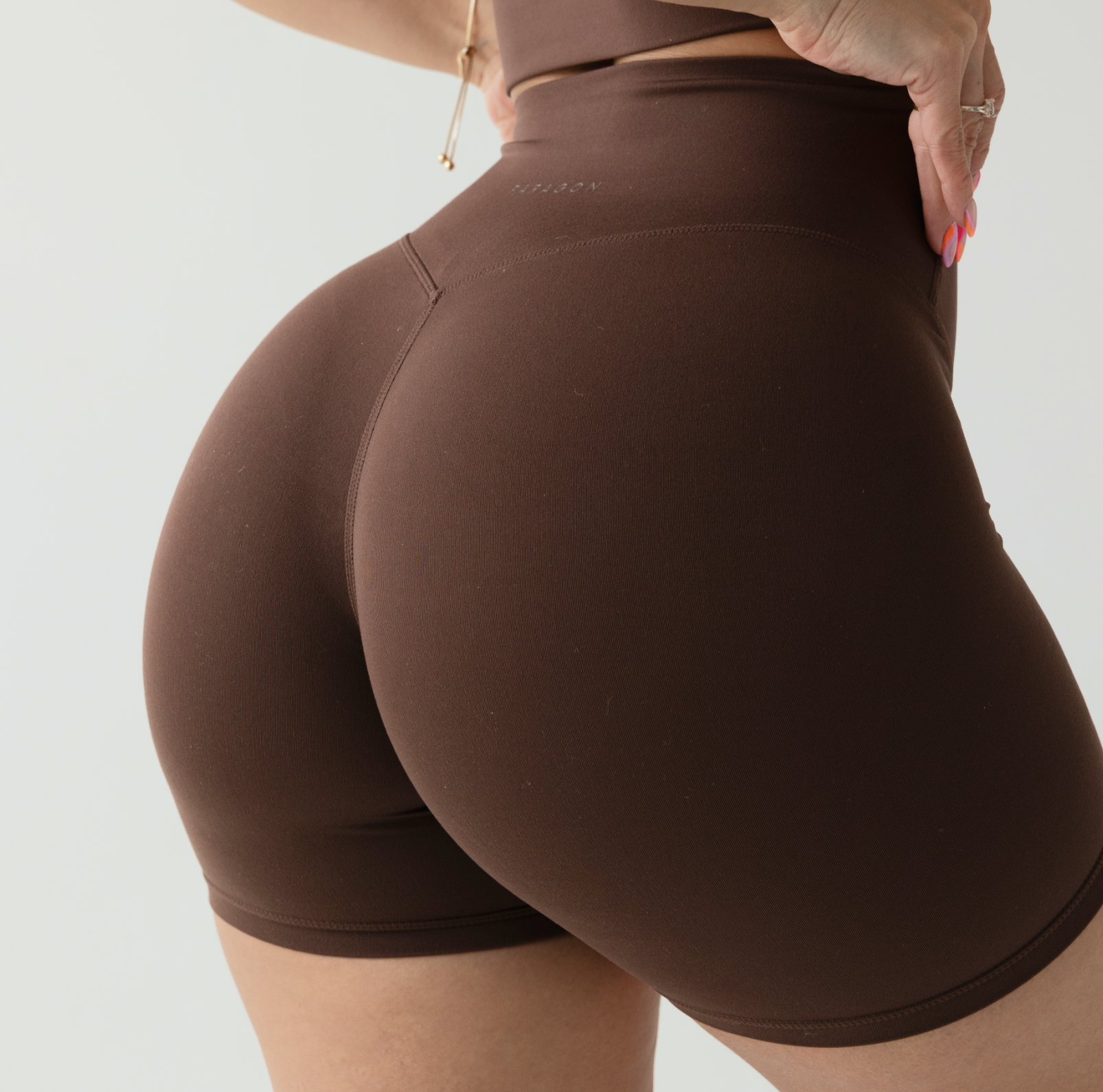 Person wearing brown athletic shorts, close-up view from the back.