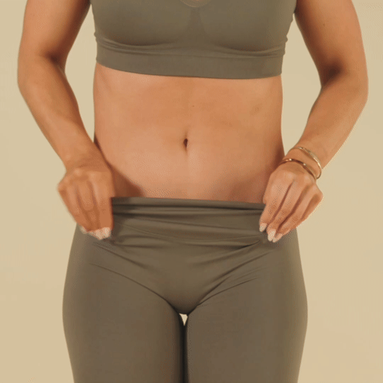 Person adjusts waistband of gray leggings.