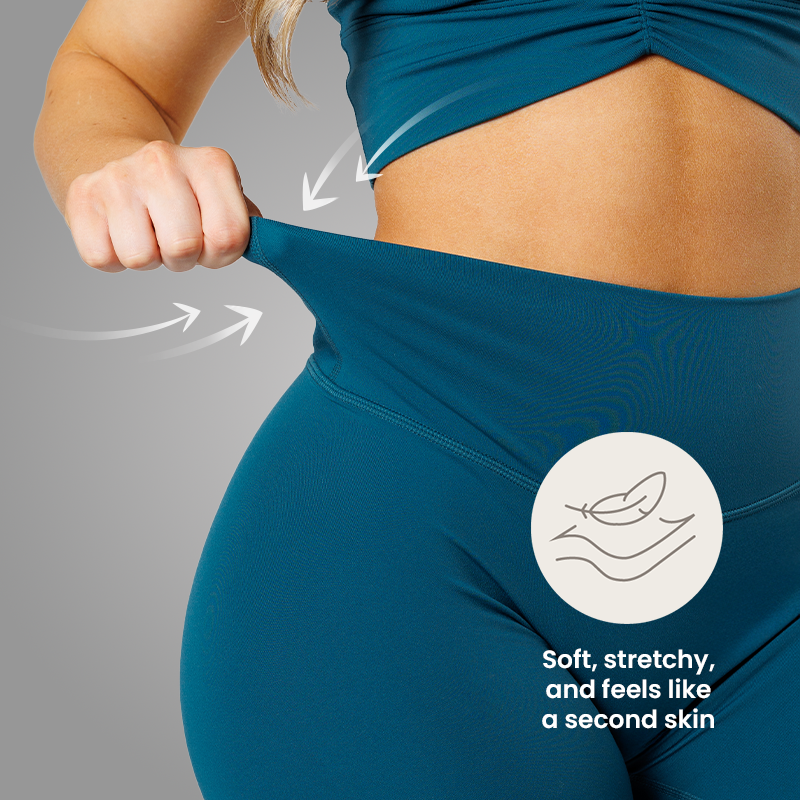A woman stretches the waistband of her teal leggings to demonstrate the fabric's flexibility.