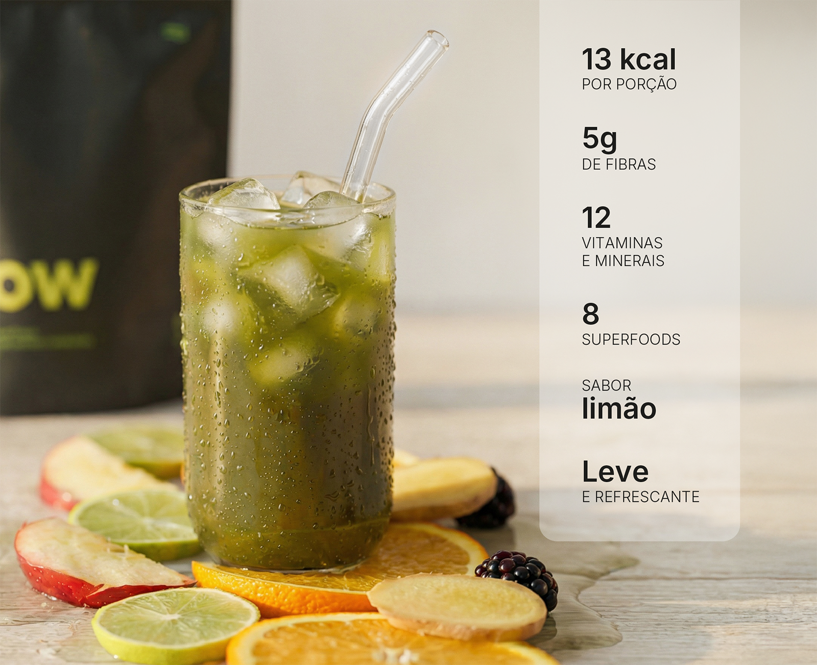 A tall glass of a green beverage with ice, surrounded by slices of fruit like orange and lime.