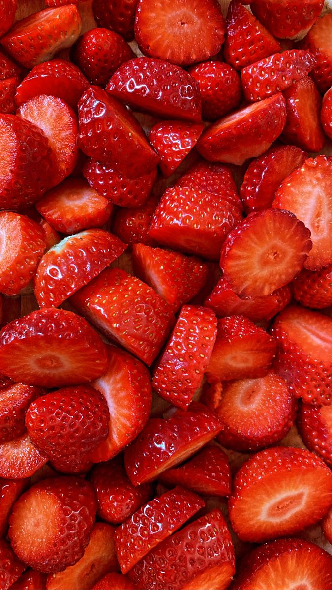 A close-up, top-down view of a large pile of freshly sliced red strawberries.