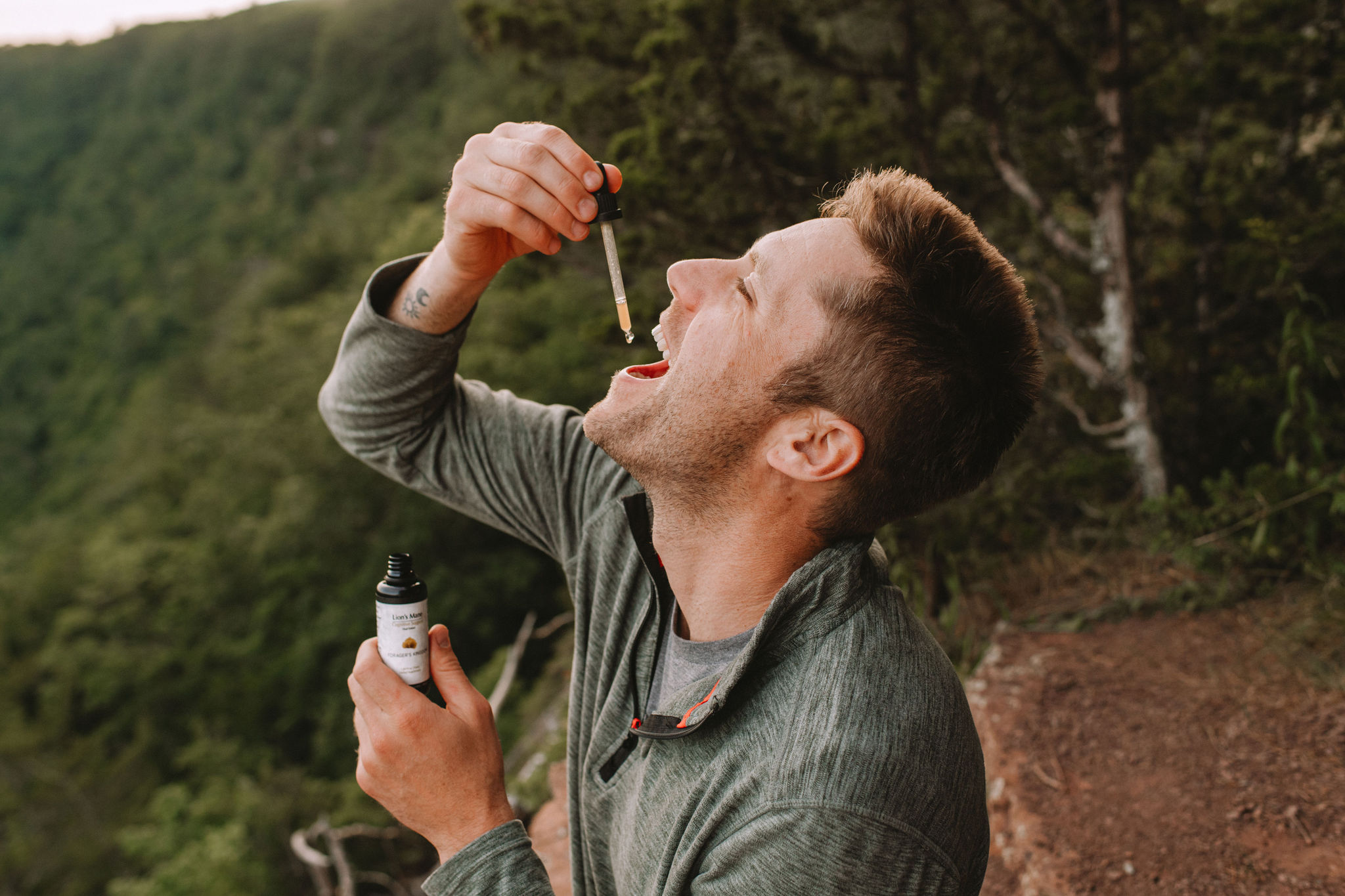 Man outdoors using a dropper to take liquid from a bottle.