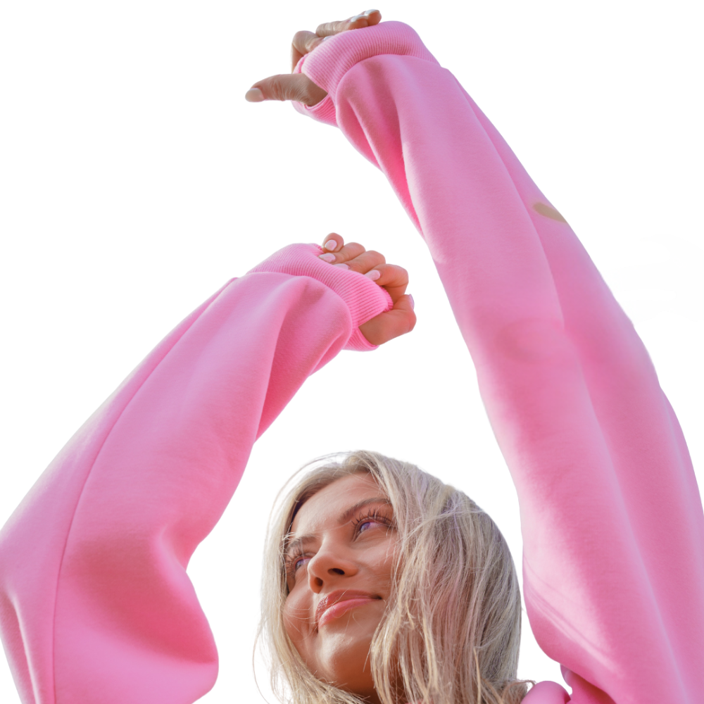 Person in a pink sweater raising arms against a clear background.