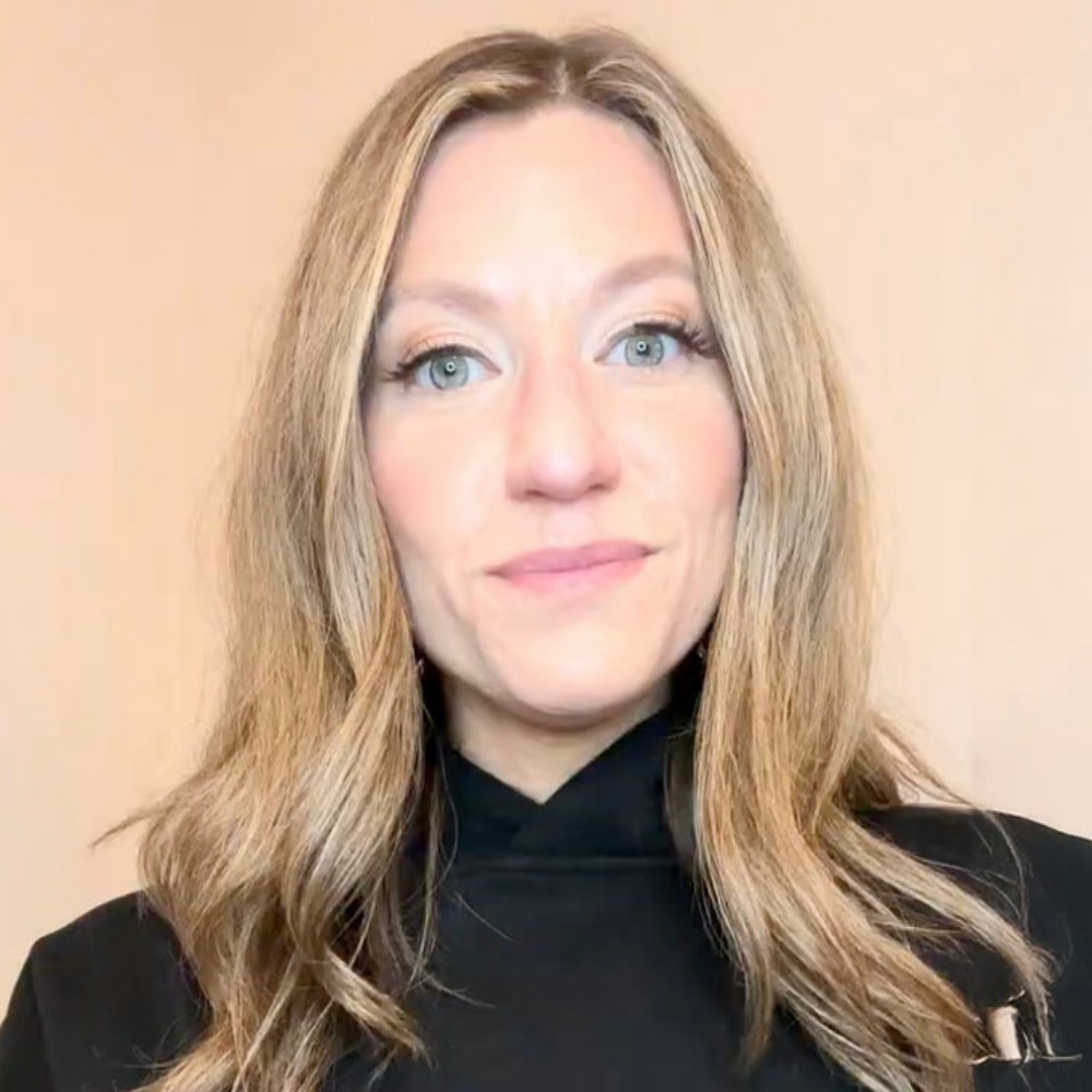 Person with long hair wearing a black top against a plain background.