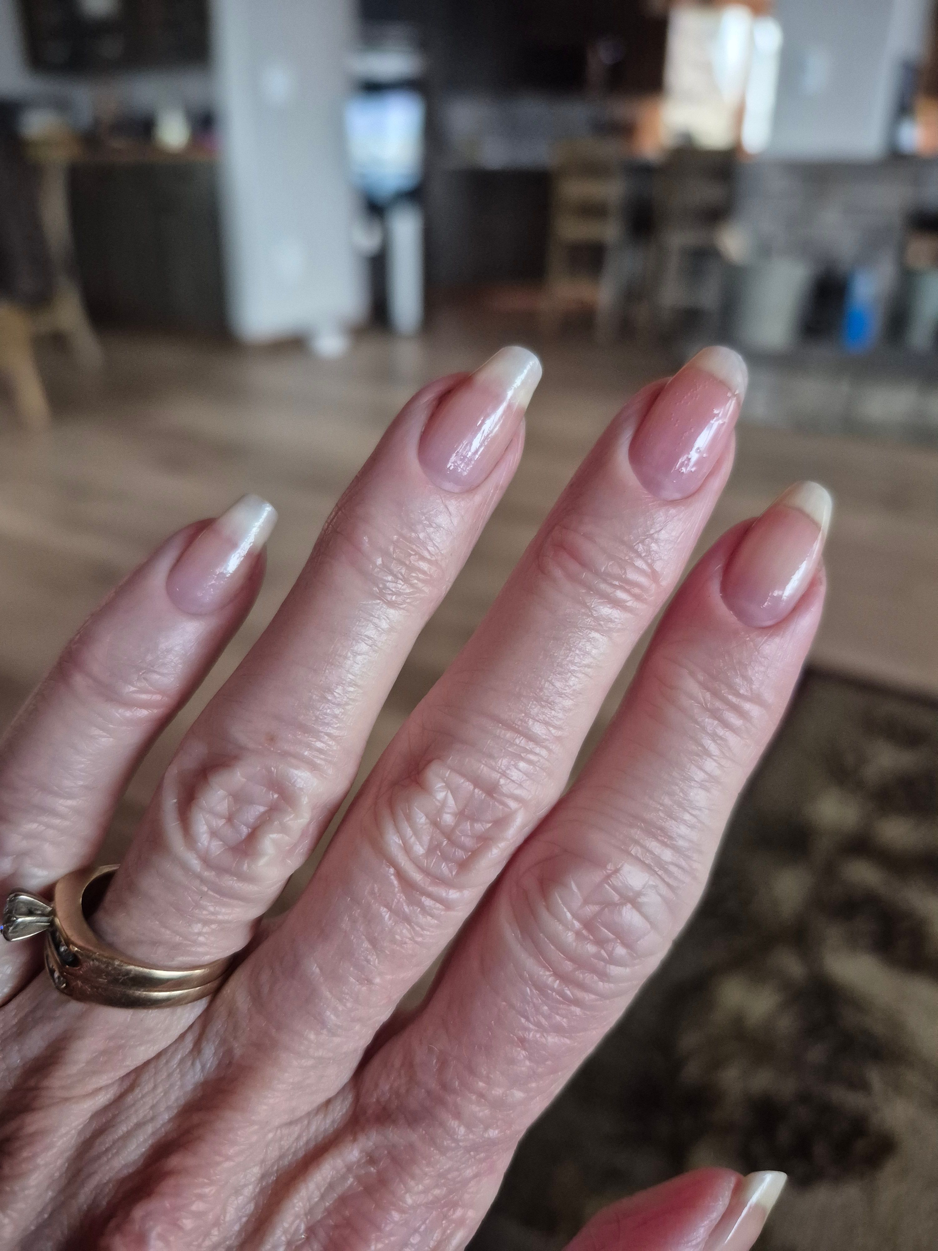 A close-up of a person's hand with long, manicured nails and a gold diamond ring.