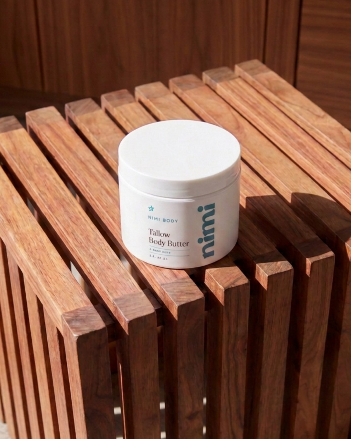 A white pump bottle of Nimi body wash resting diagonally on a slatted wooden bench.