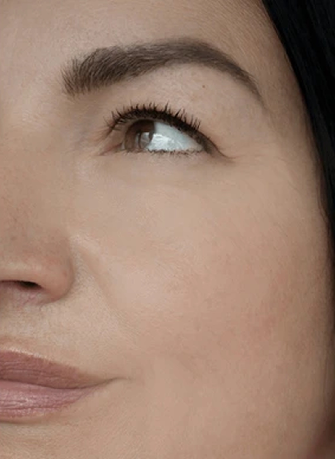 A close-up of the right side of a woman's face, showing her eye looking up, nose, and mouth.