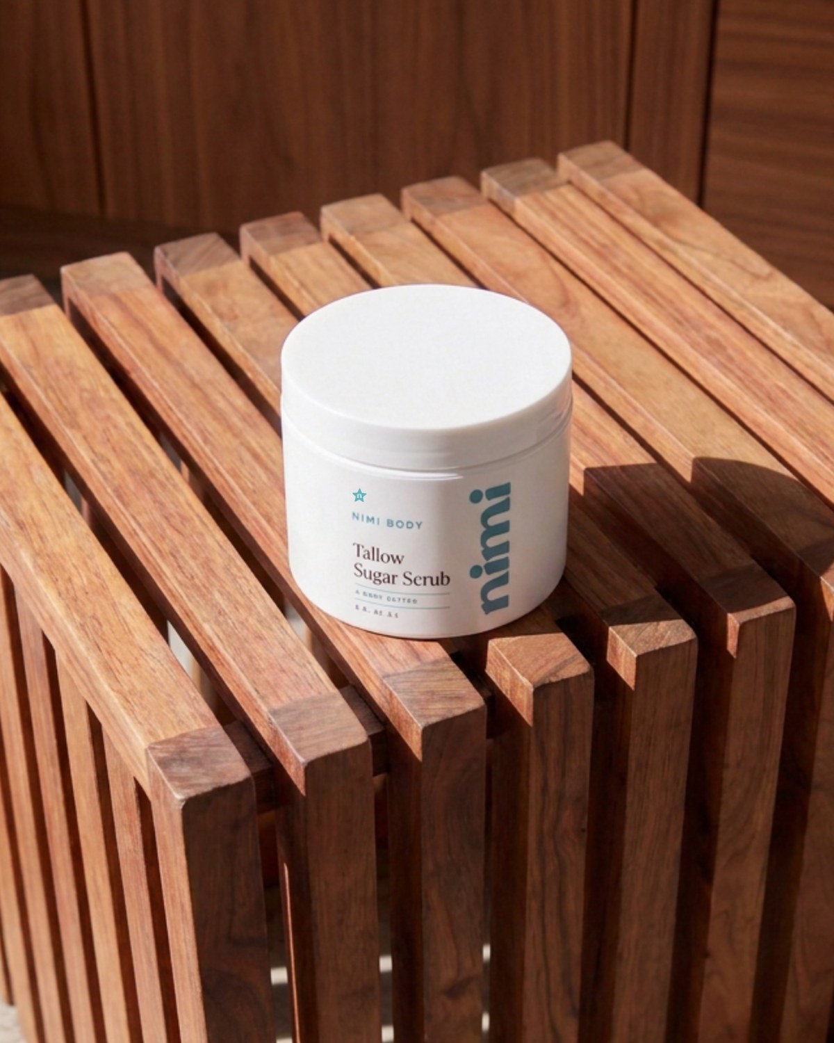 A white pump bottle of Nimi body wash resting diagonally on a slatted wooden bench.
