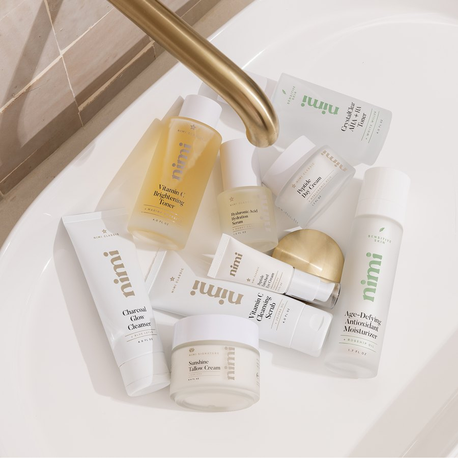 An overhead view of various nimi brand skincare products arranged in a white bathroom sink.