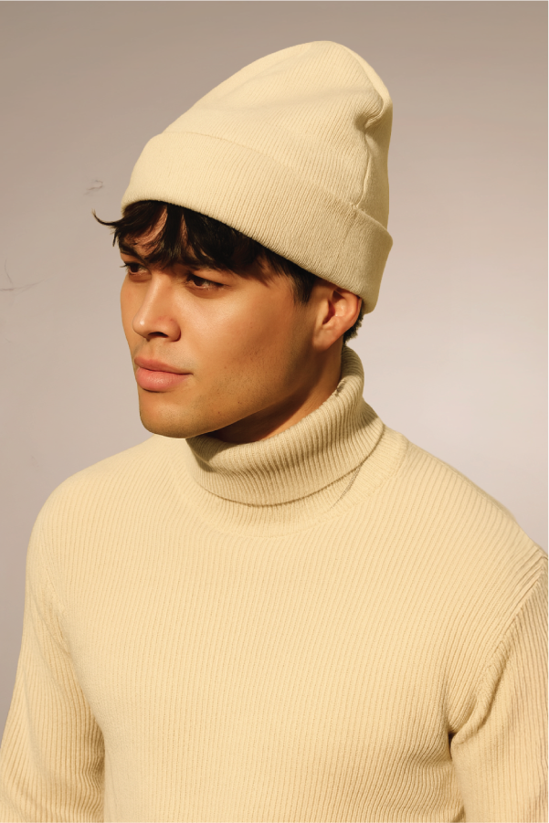 Person wearing a beige beanie and turtleneck sweater, looking sideways.