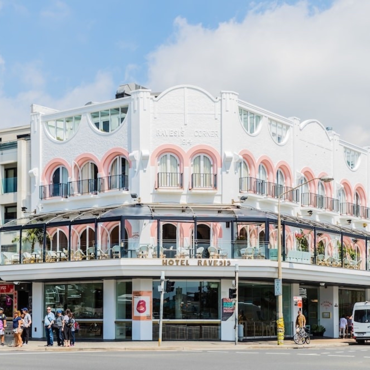 White and pink building with arched windows, labeled 'HOTEL RAVESIS' on a sunny day.