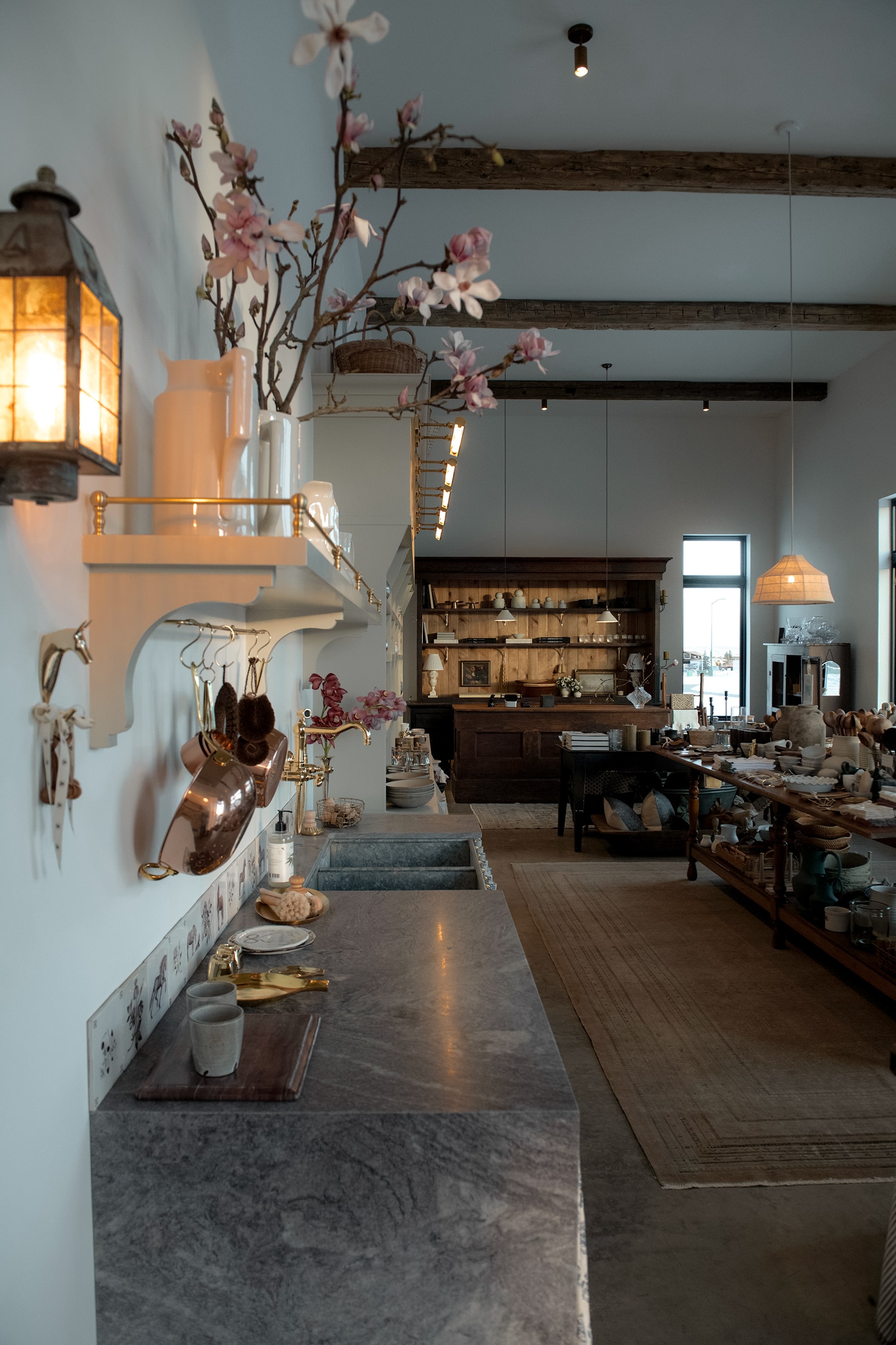Cozy kitchen with stone countertops, shelves, and hanging pots, illuminated by soft lighting.