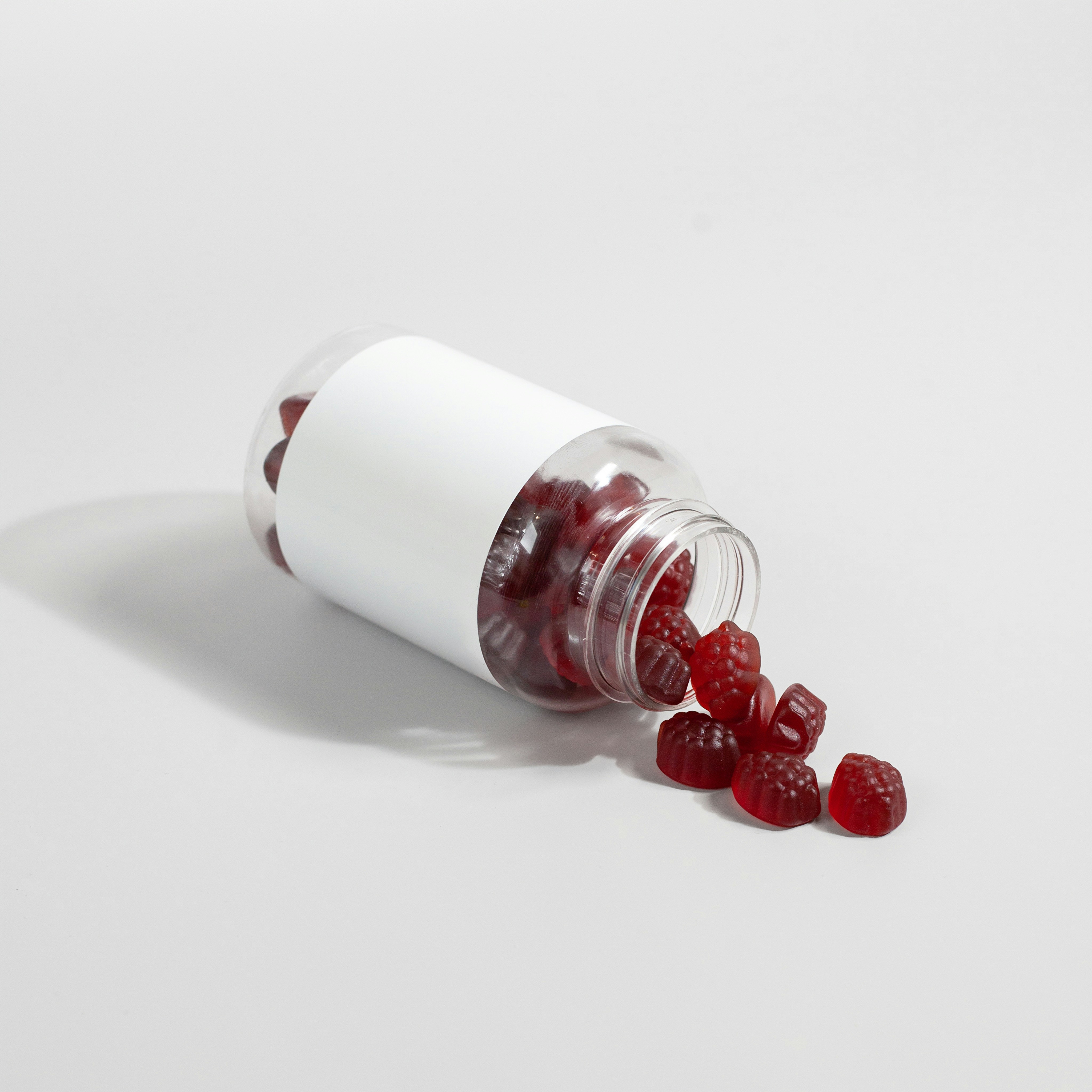 Open bottle with red gummy candies spilling out.