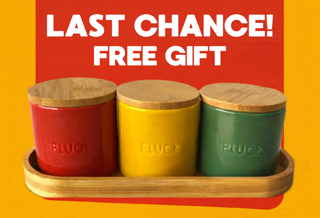 A set of three canisters in red, yellow, and green with wooden lids in a wooden tray.