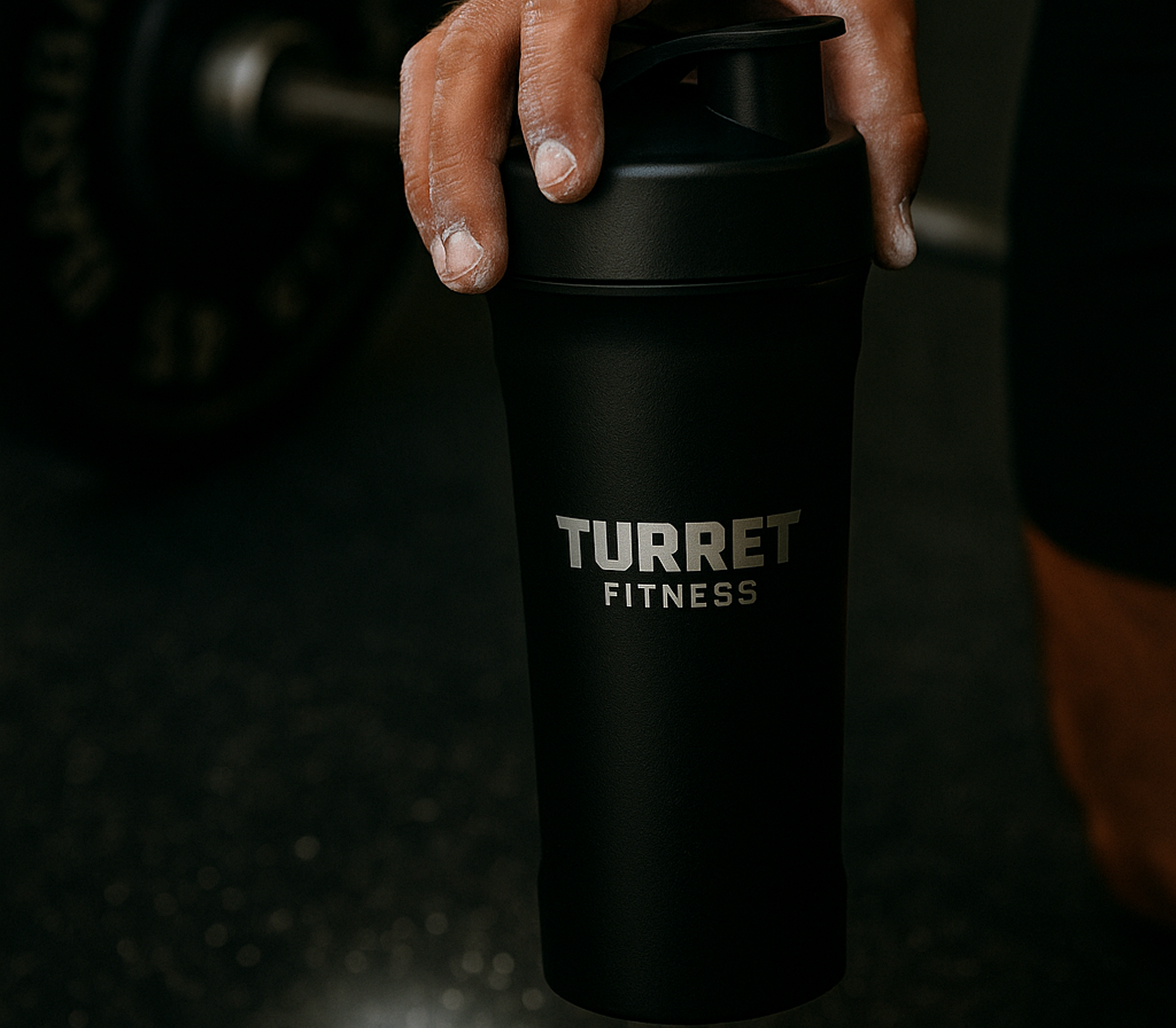 Hand holding a black Turret Fitness shaker bottle.