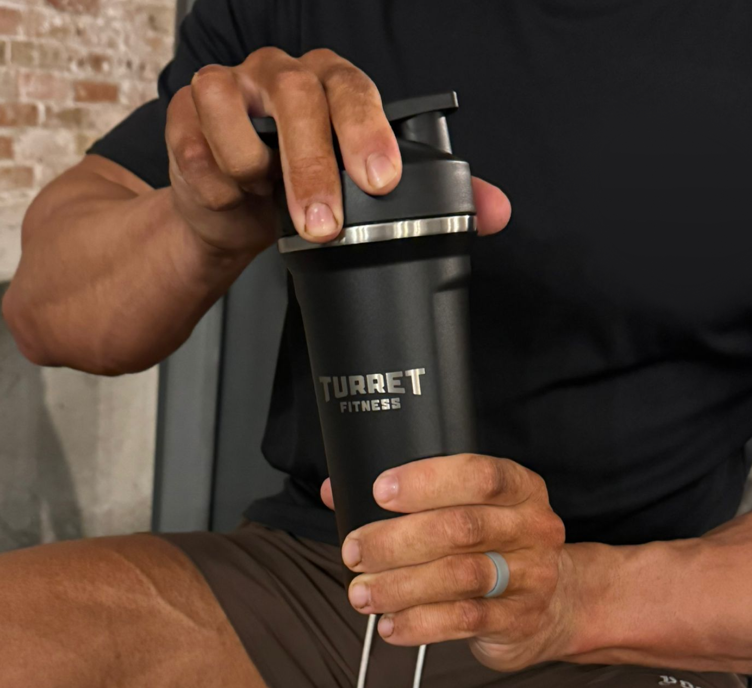 Person holding a black Turret Fitness shaker bottle.