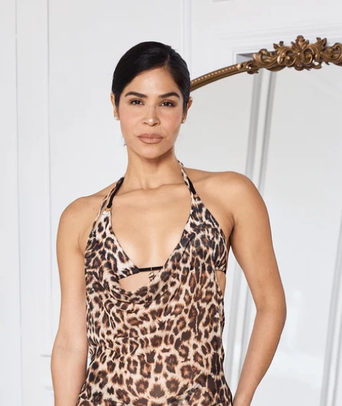 Person wearing leopard print dress stands in front of mirror.