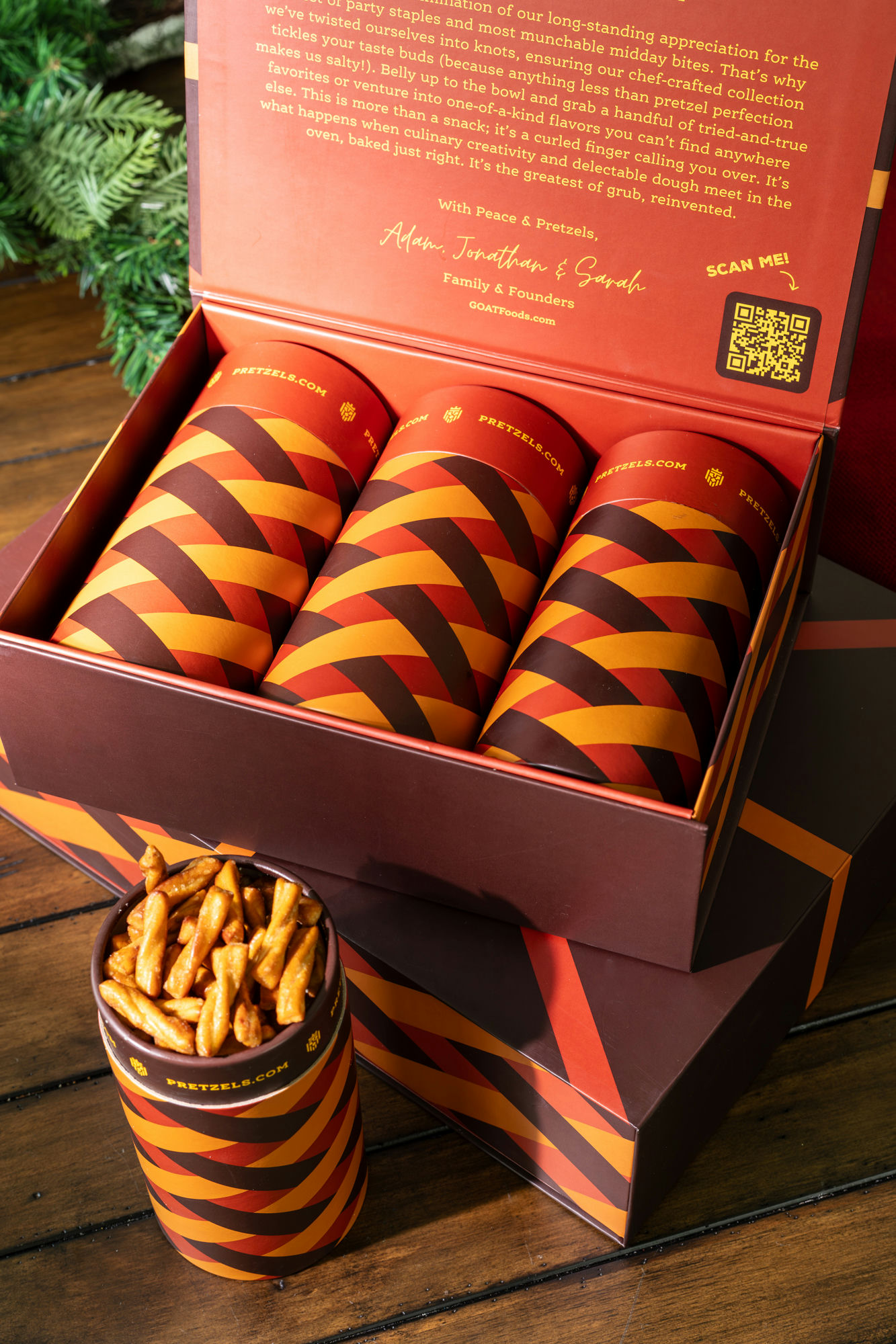 Box of snack containers with a QR code and cup of pretzel sticks on a wooden table.