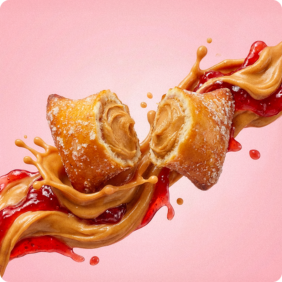 A sugar-coated pastry filled with peanut butter, split open amidst a splash of peanut butter and jelly.