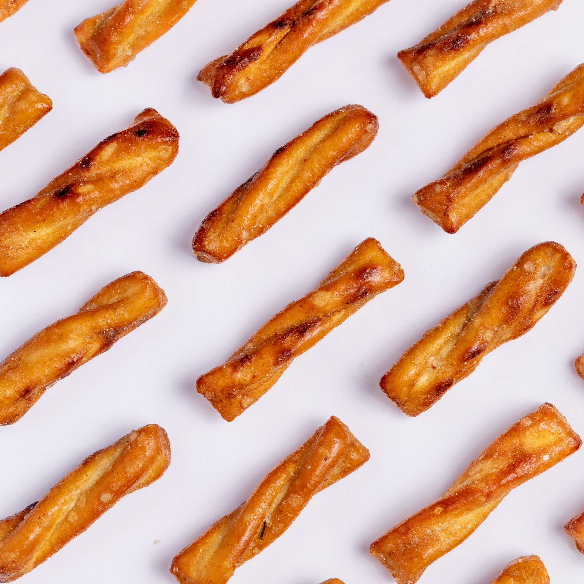 Twisted pastries arranged in a diagonal pattern on a white background.