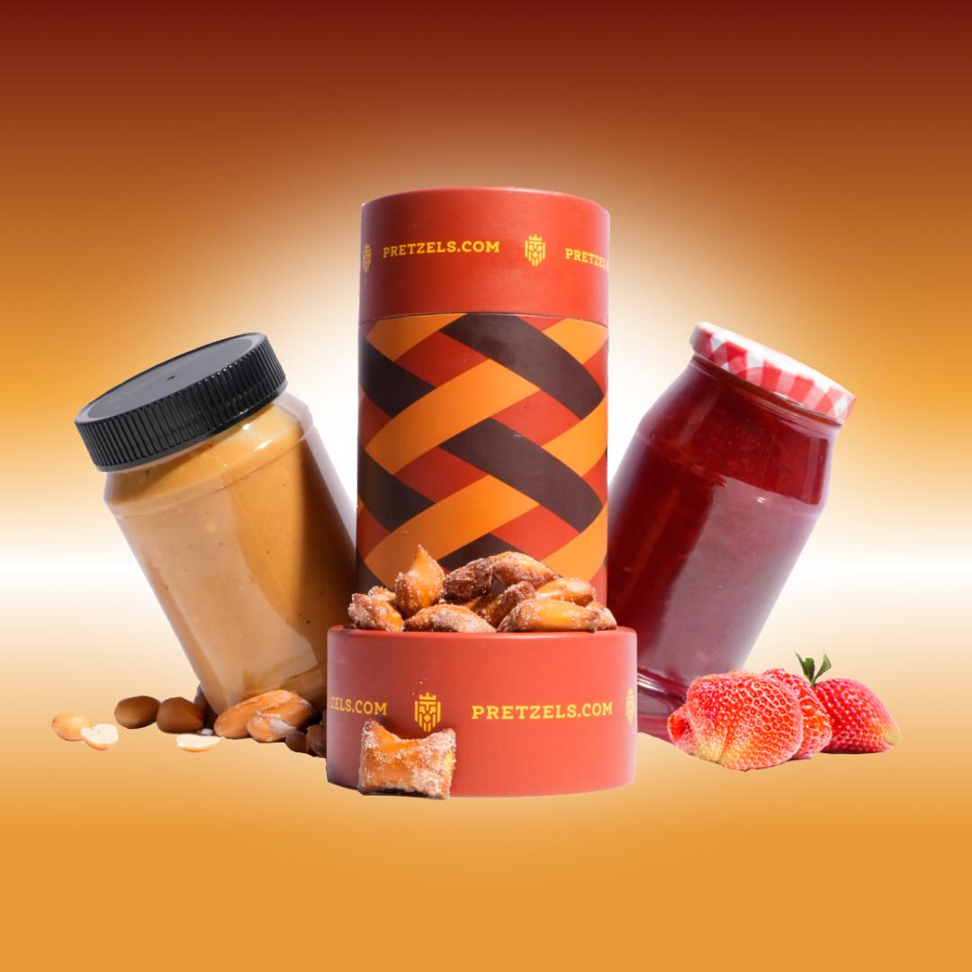 Assorted pretzels, peanut butter, jam, and strawberries against a gradient orange background.