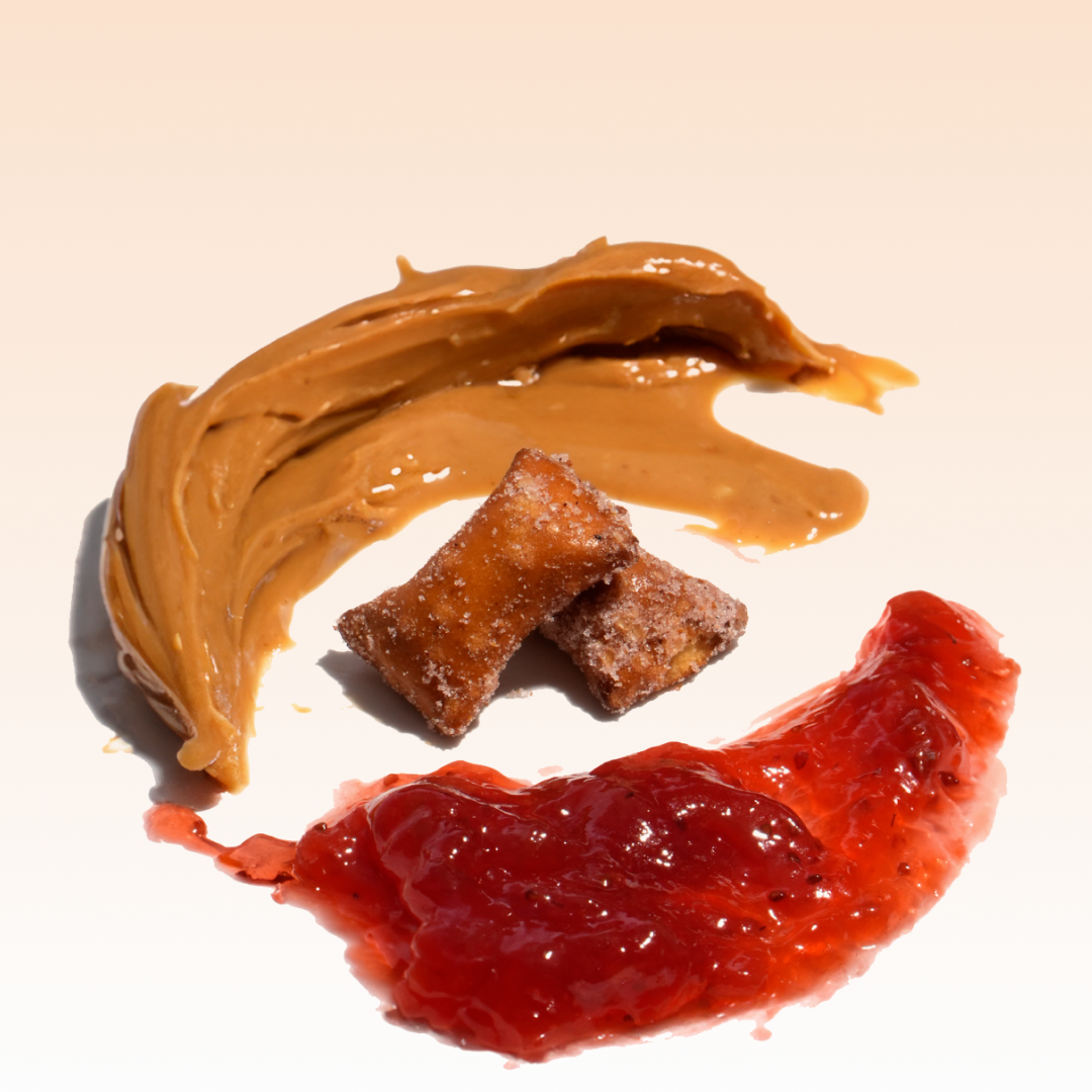 Peanut butter, jelly, and two small pastries arranged on a white surface.