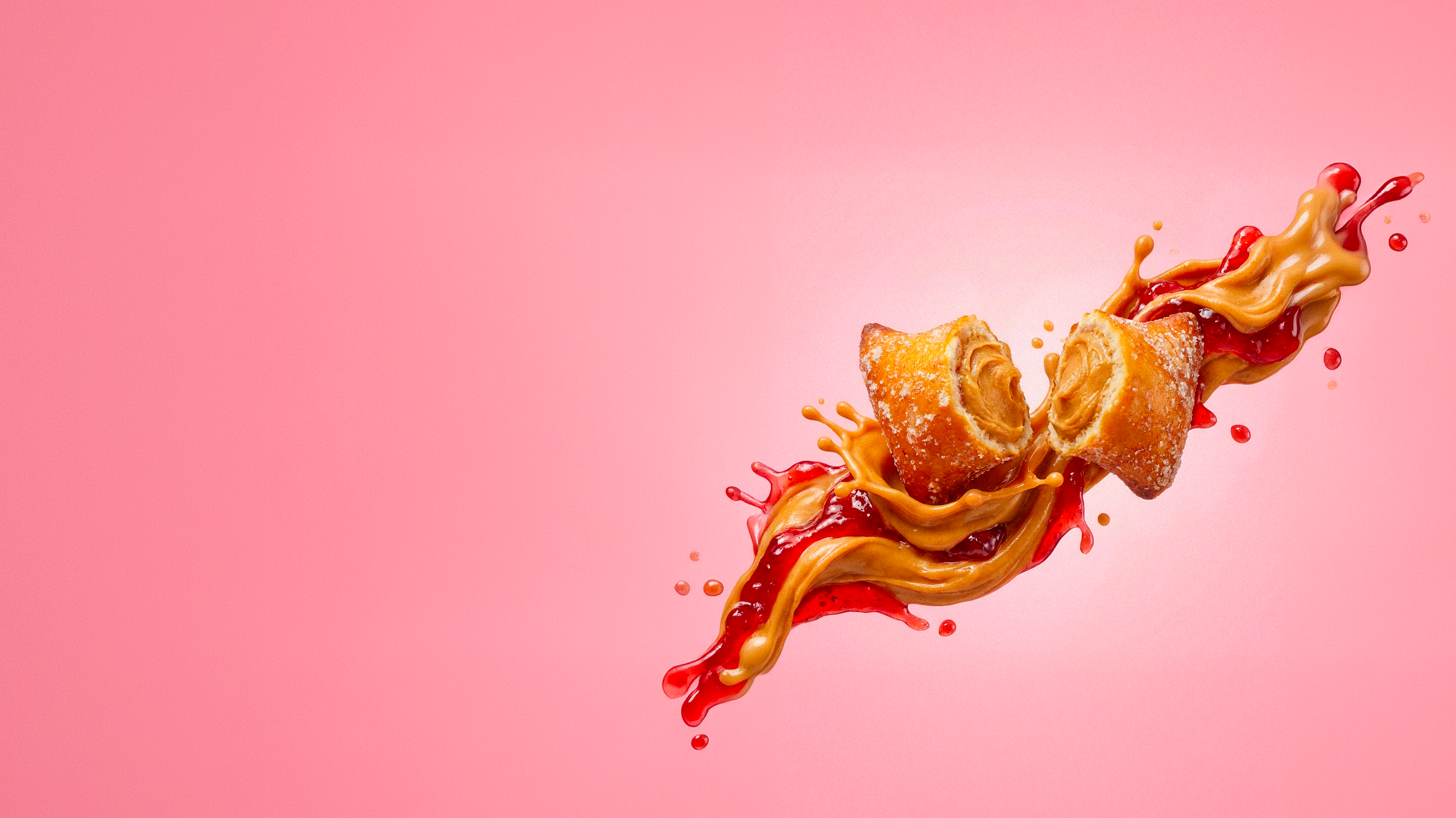 Two peanut butter-filled pastries splashing in peanut butter and jelly against a pink background.