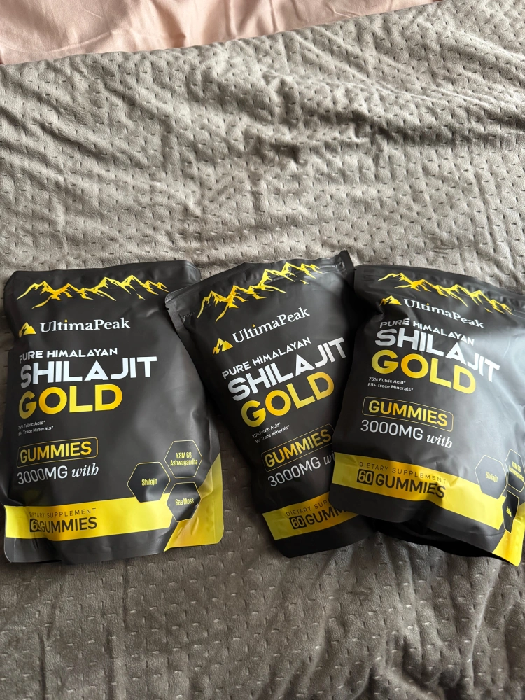 Three bags of UltimaPeak Shilajit Gold gummies on a textured surface.