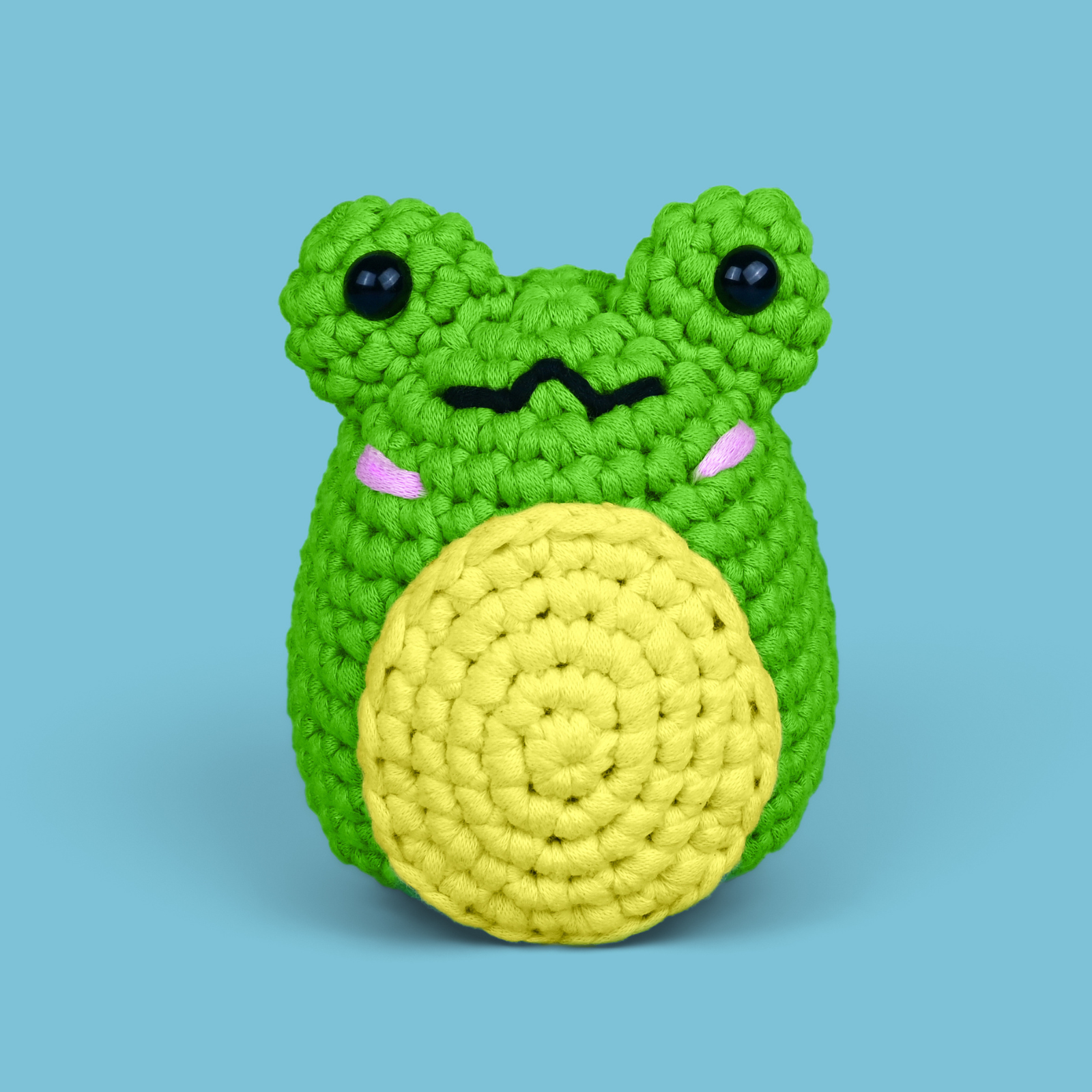 Crocheted green frog with a yellow belly on a blue background.