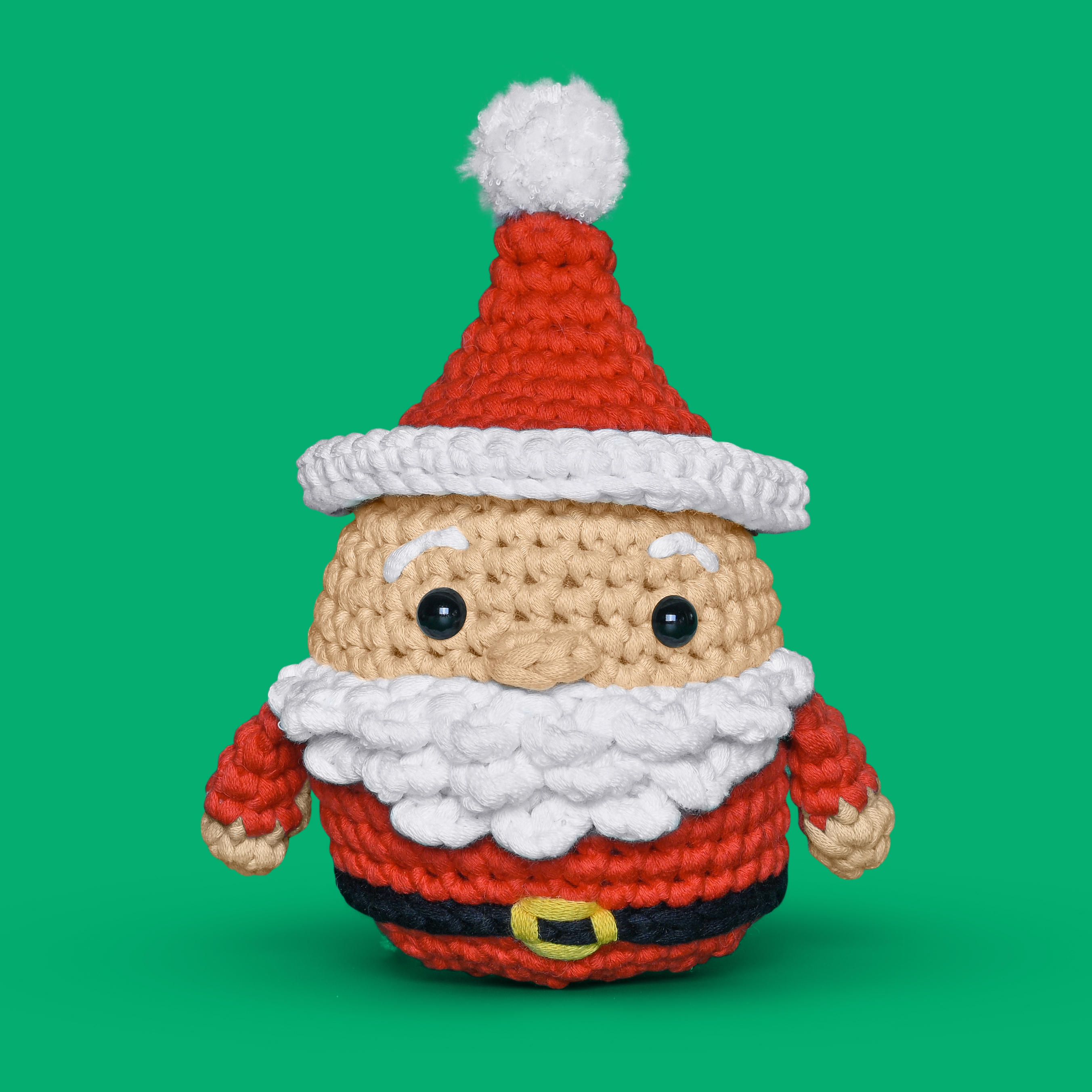 Crocheted Santa Claus toy against a green background.