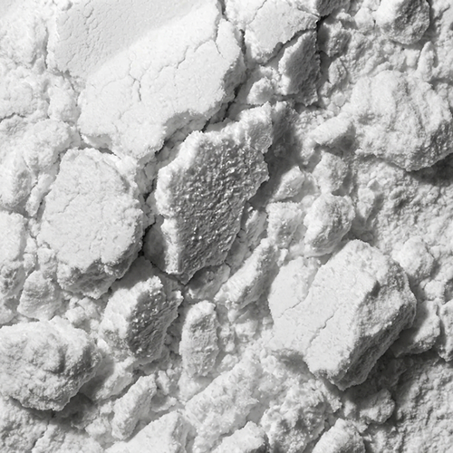 A close-up, black and white photo of a clumpy, white powder.