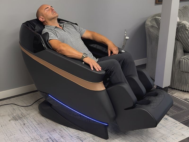 Person relaxing in a reclining massage chair indoors.