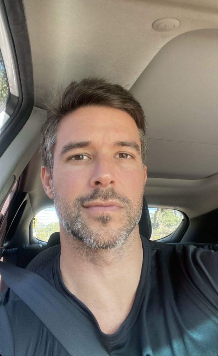 Person sitting in a car wearing a seatbelt, looking at the camera.