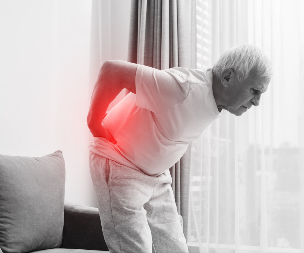 Elderly man holding his lower back in pain, with a red highlight.