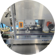 A close-up, circular-cropped photo of a stainless steel industrial machine with rollers and a control dial.