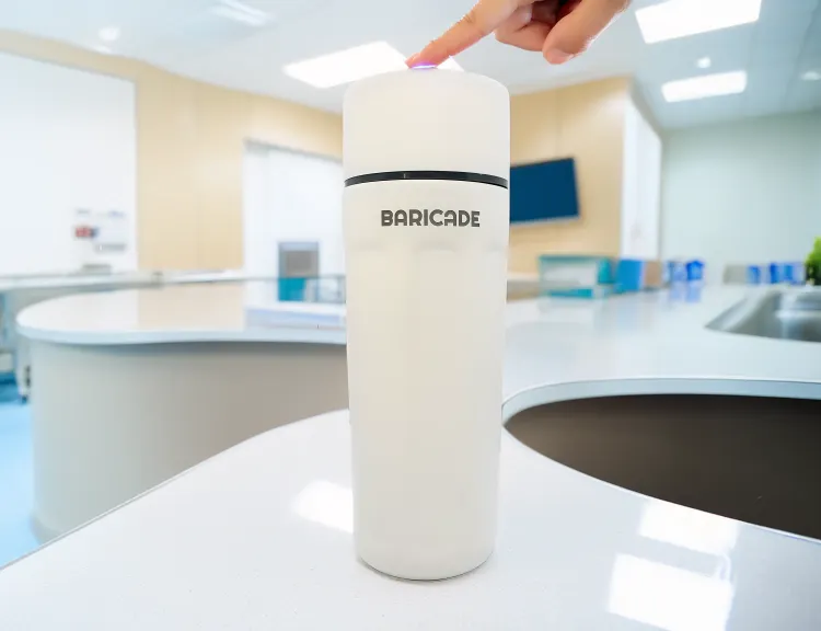 White cylindrical device labeled 'BARICADE' on a table, finger pressing top button.