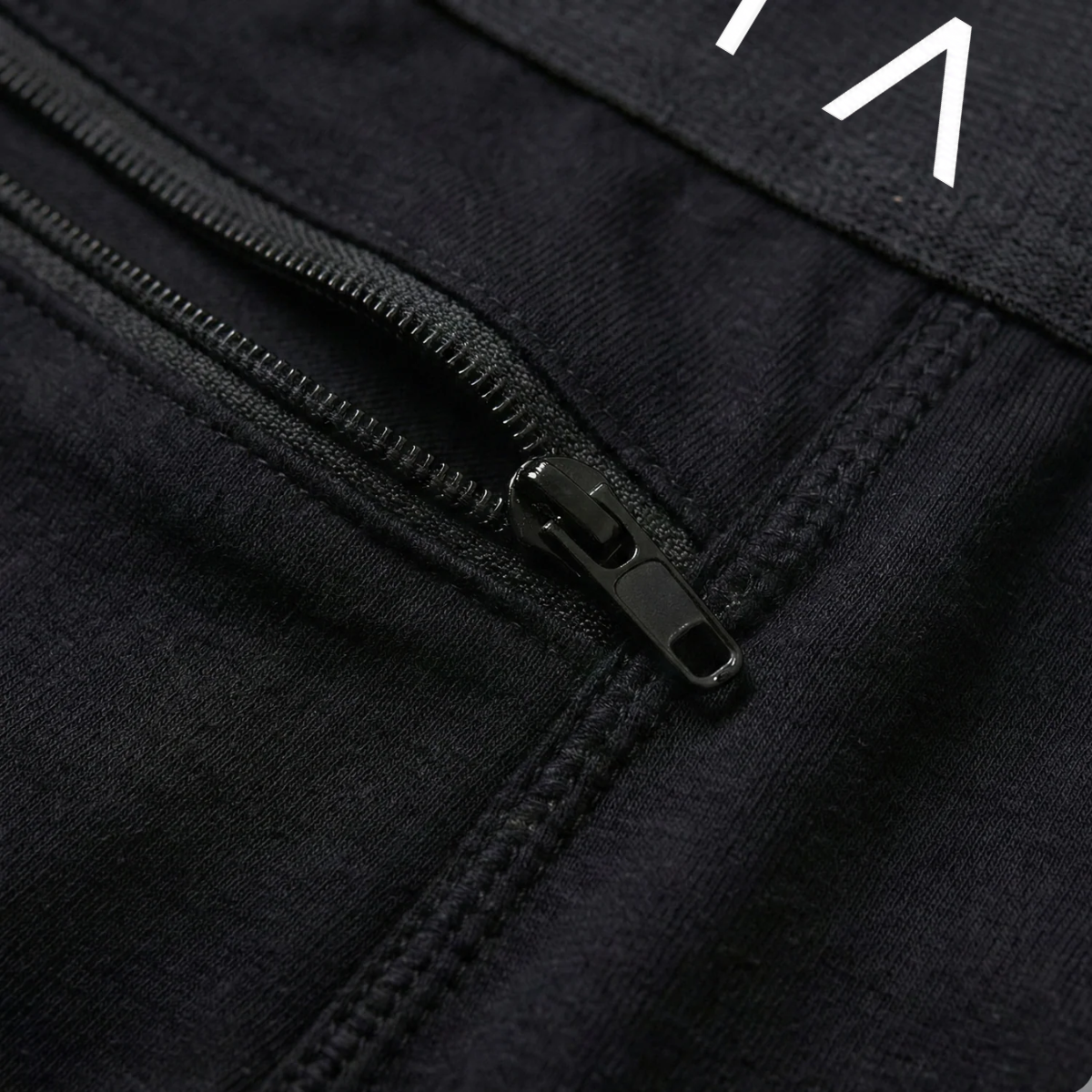 A close-up of a black zipper on the pocket of a black garment with a white graphic.