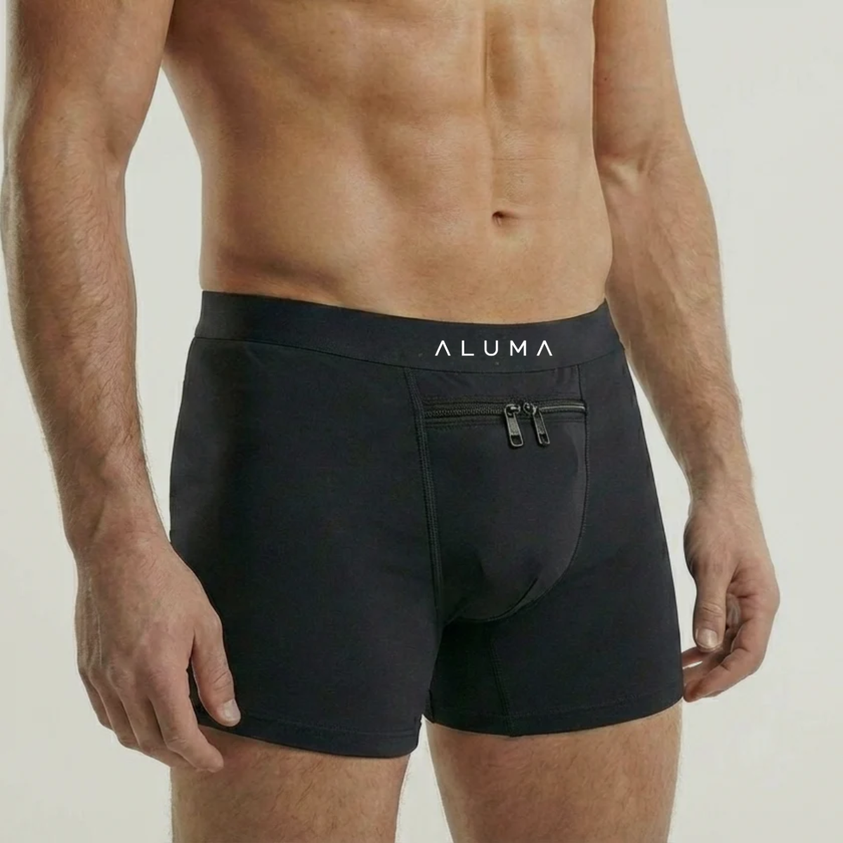 A man's torso wearing black boxer briefs with the word ALUMA on the waistband and a zippered pocket.
