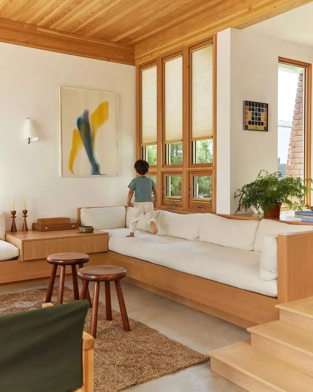 Child walking on a white sofa in a cozy, wooden living room.