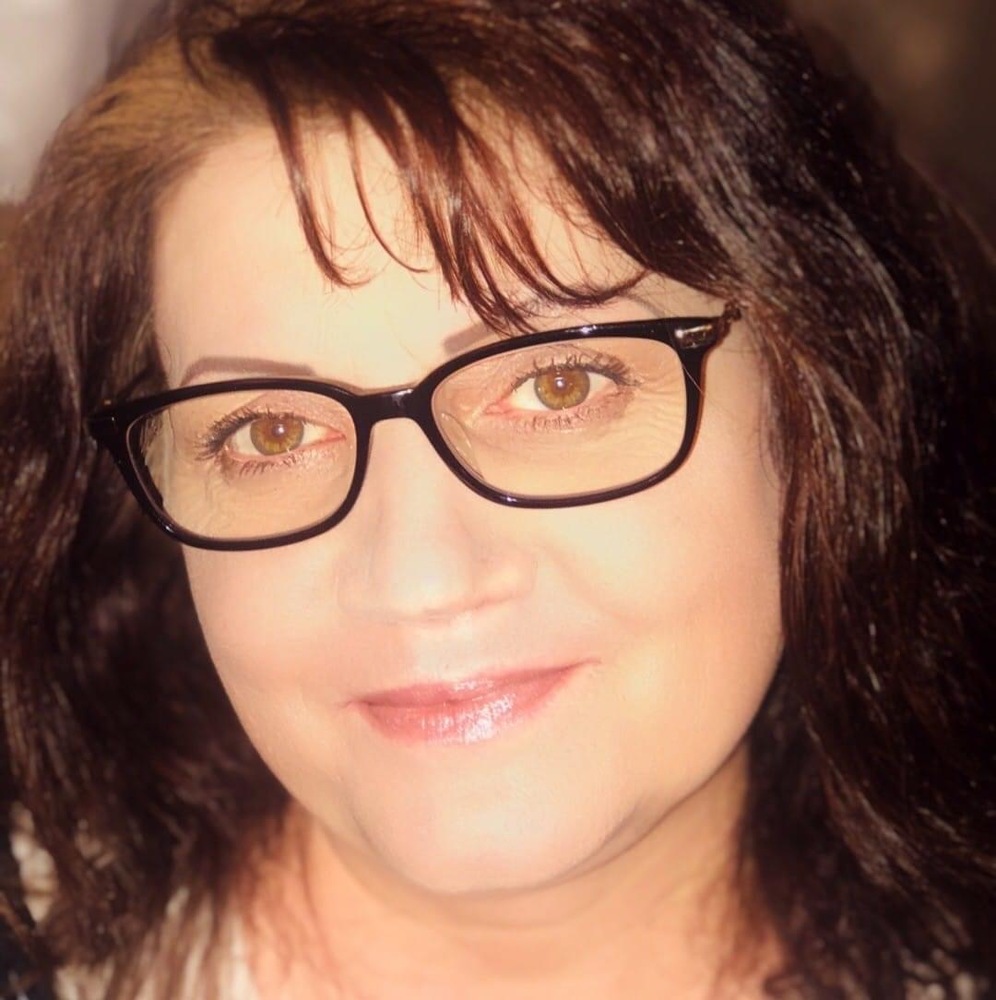 A person with glasses and dark hair smiling at the camera.