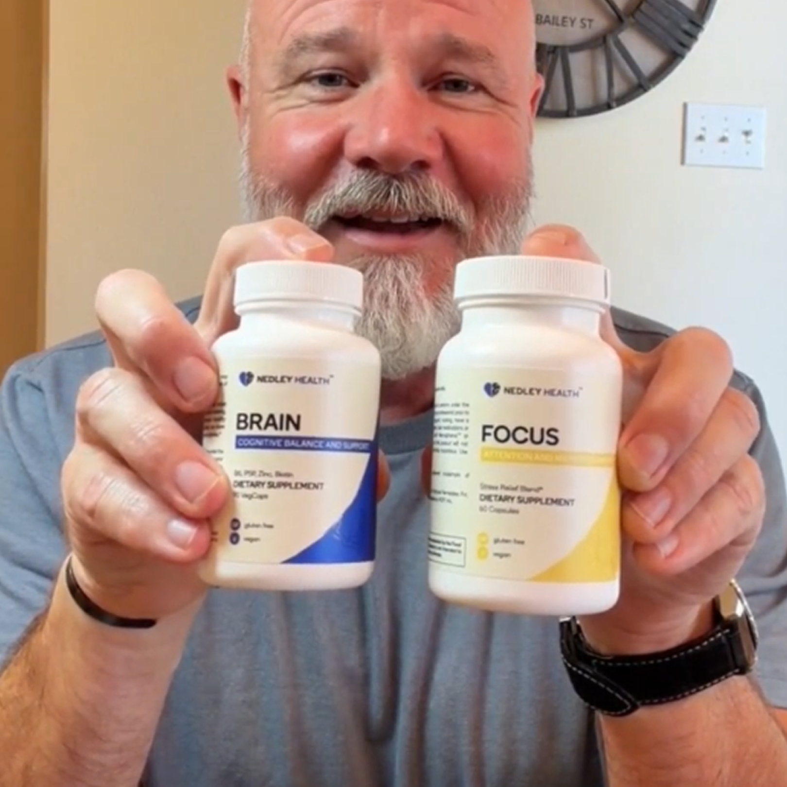 A smiling man holds up two white bottles of Nedley Health dietary supplements, labeled Brain and Focus.