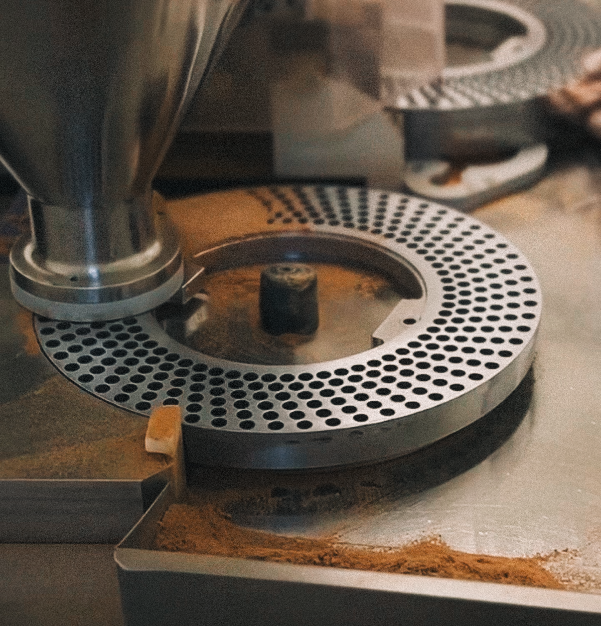 Close-up of industrial machinery with metal components and scattered powder.