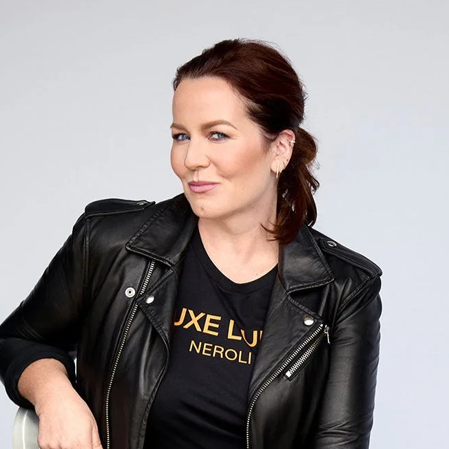 Person in a black leather jacket and black shirt, smiling slightly.