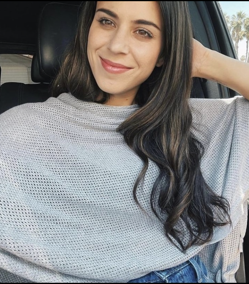 Person with long dark hair smiling in a car.