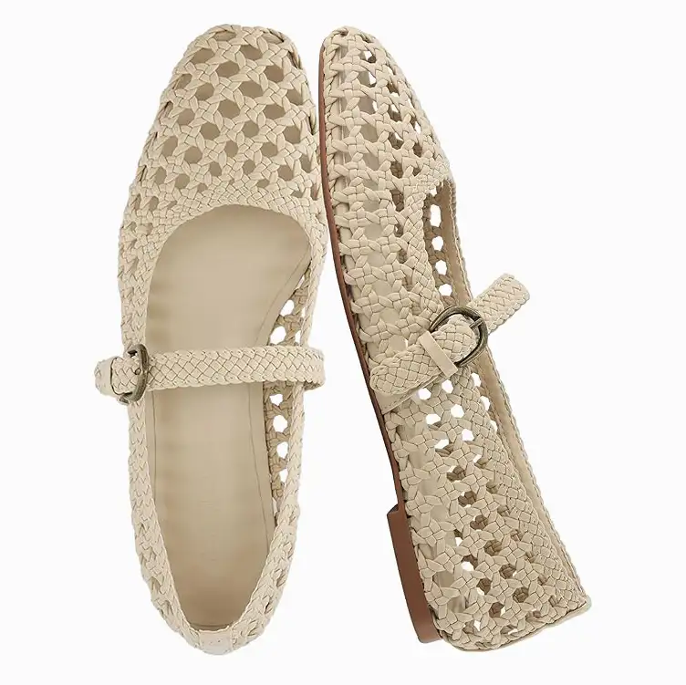 A pair of cream-colored, woven Mary Jane style flat shoes on a white background.
