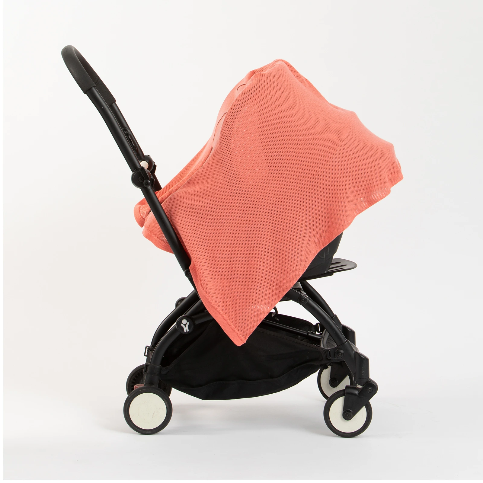 A stroller with a coral-colored cover draped over it.