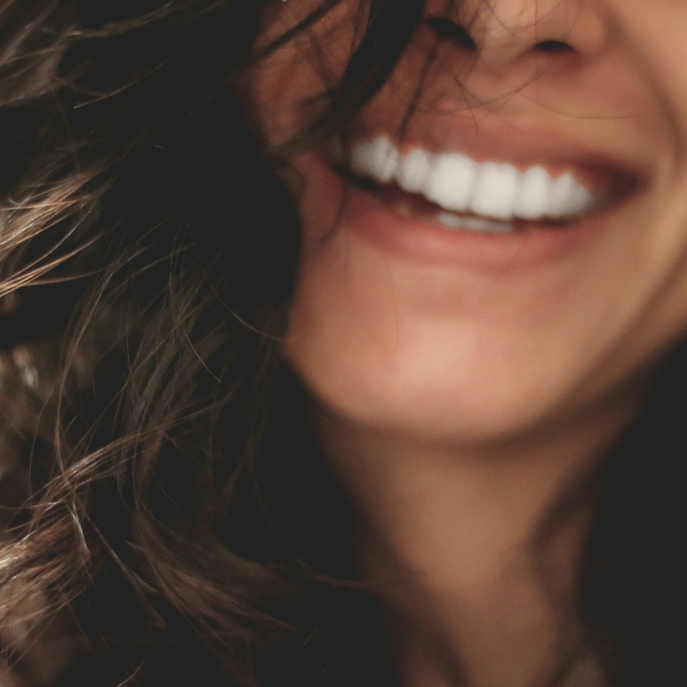 Close-up of a person smiling with wavy hair in the foreground.