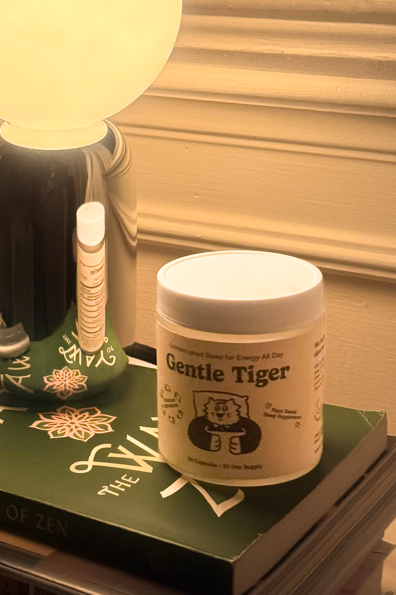 A jar labeled 'Gentle Tiger' on a book beside a lamp.